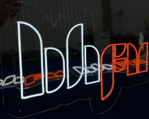 Comunicação visual Letreiro neon LED branco e laranja em acrílico, contornos iluminados com reflexo no painel escuro